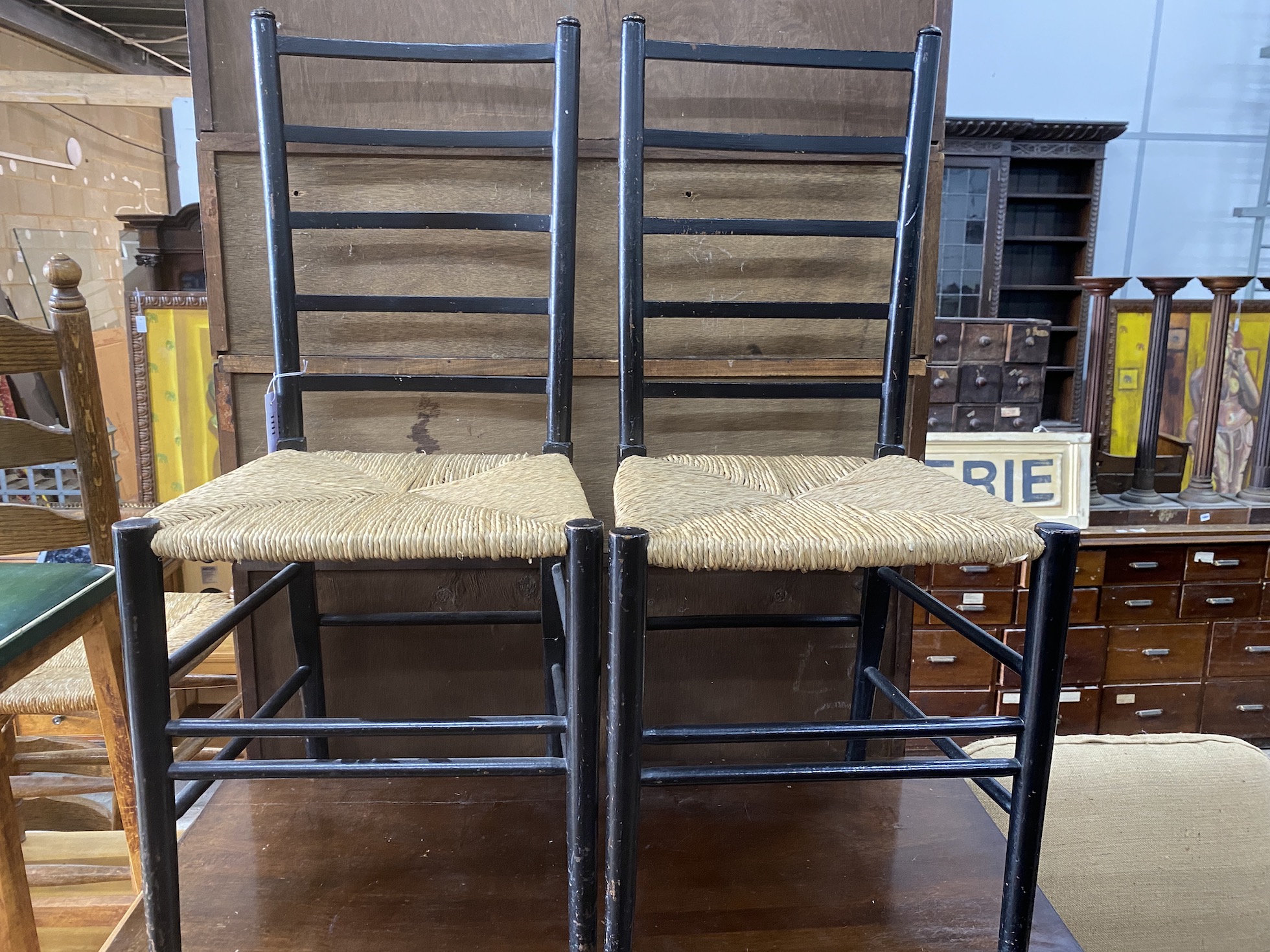 A pair of Arts & Crafts style ebonised rush seat dining chairs and a mid century beech stool